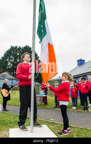Durrus, Irlanda. Il 15 marzo, 2016. Gli alunni Stephen Dukelow e Anna Walker alzare il tricolore irlandese mentre gli altri alunni guardare al St James Scuola nazionale, Durrus, sulla proclamazione giorno che era stata organizzata per commemorare gli eventi del 1916. Credito: Andy Gibson/Alamy Live News. Foto Stock