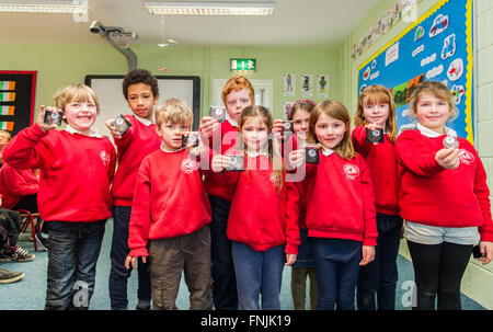 Durrus, Irlanda. Il 15 marzo, 2016. Gli alunni della classe Junior mostrano le medaglie hanno ricevuto in occasione del centesimo anniversario della proclamazione giorno a St James Scuola nazionale, Durrus, che è stata organizzata per commemorare gli eventi del 1916. Credito: Andy Gibson/Alamy Live News. Foto Stock