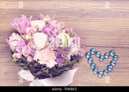 Fiori di San Valentino con gioielli heartshaped sfondo di legno Foto Stock