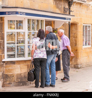 Le persone in cerca di un Agenti Immobiliari finestra in Broadway , Worcestershire , Inghilterra , Inghilterra , Regno Unito Foto Stock