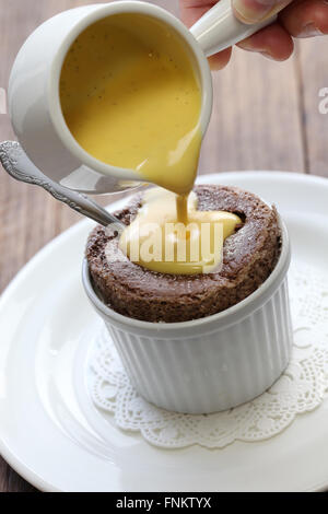 Versando una crema anglaise al cioccolato souffle, francese dessert Foto Stock