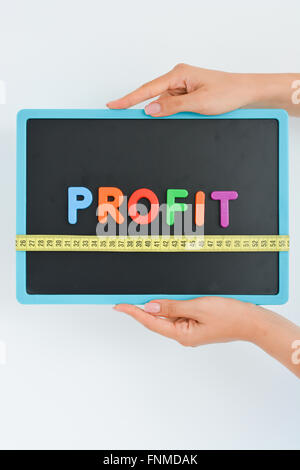 Misurare il concetto di profitto scritto come colorato magnetico lettera blocchi con scala Foto Stock