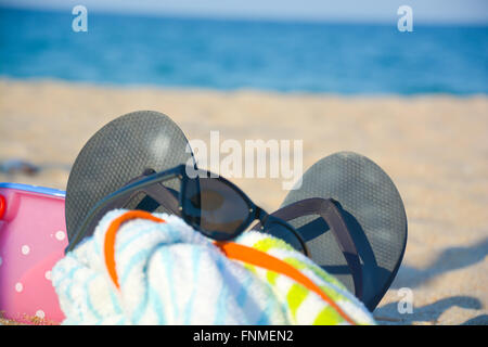 Spiaggia accessori come occhiali da sole, pantofole, asciugamano, giocattoli sulla sabbia Foto Stock