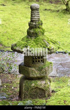 Vecchia lanterna di pietra coperta di verde muschio al giardino giapponese Foto Stock