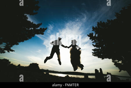 Lo sposo e la sposa jumping contro il bellissimo cielo Foto Stock