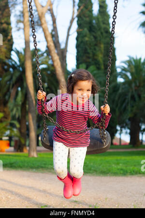 Felice bambina di tre anni avente divertimento su uno swing Foto Stock