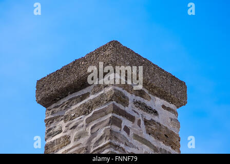 Top di vecchi mattoni e malta camino sul cielo blu chiaro. Foto Stock