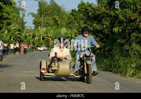 Presidente Rafael Correa e Peter Greenberg guidare una motocicletta vintage con un sidecar passato persone locali nella regione di Cacao durante le riprese di Ecuador: Royal Tour. Foto Stock