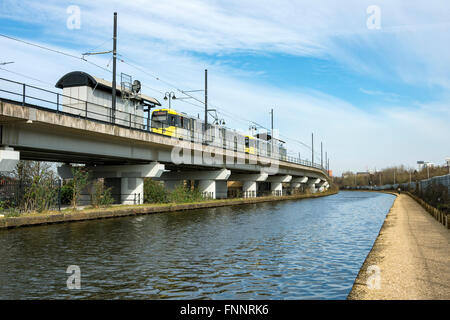 Tram Metrolink presso il Pomona stop sul viadotto accanto al Bridgewater Canal, Manchester, Inghilterra, Regno Unito Foto Stock