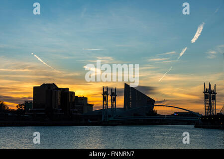 Il Quay West edificio, Imperial War Museum North e il Lowry passerella al tramonto, Salford Quays, Manchester, Inghilterra, Regno Unito Foto Stock