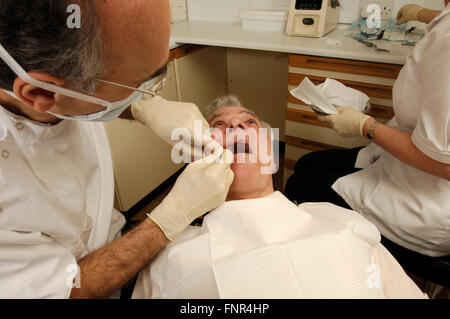 Un dentista esamina la condizione dei suoi pazienti denti. Foto Stock