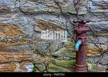 Vecchio arrugginito rubinetto di acqua sul lato dell'edificio Foto Stock