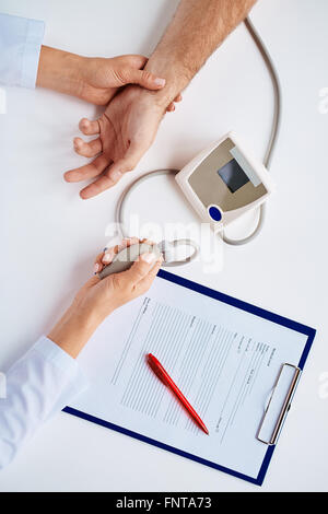 Le mani del terapeuta con il tonometro di misurare la pressione del sangue del paziente Foto Stock