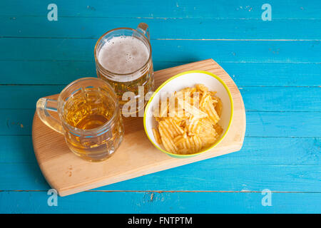 Patate fritte e due tazze di birra sul tavolo Foto Stock