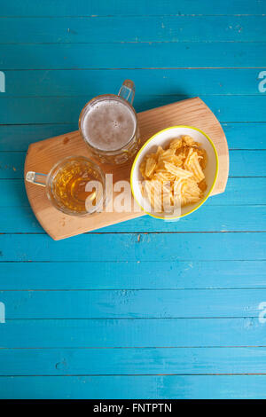 Patate fritte e due tazze di birra sul tavolo Foto Stock