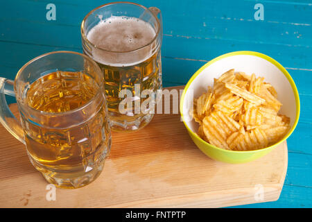 Patate fritte e due tazze di birra sul tavolo Foto Stock