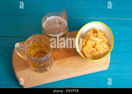 Patate fritte e due tazze di birra sul tavolo Foto Stock