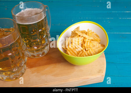 Patate fritte e due tazze di birra sul tavolo Foto Stock