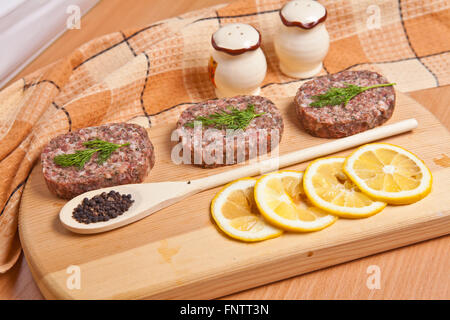 Costolette di greggio con le fette di limone su un tagliere Foto Stock