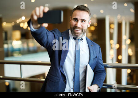 Happy businessman con sorriso toothy rendendo la sua selfie Foto Stock