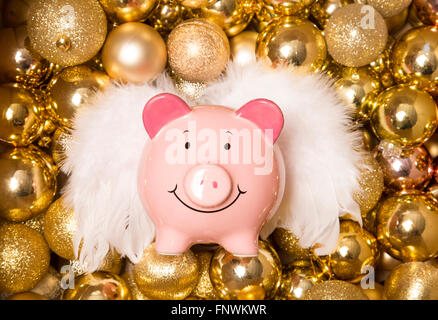 Risparmio di denaro a Natale piggybank su oro baubles Foto Stock