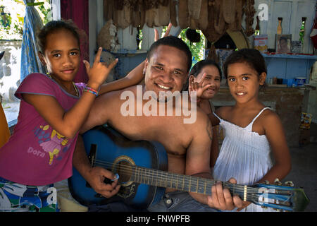 Interno di una casa tradizionale in Rangiroa, Tuamotus isole, Polinesia francese, South Pacific. Uomo a suonare la chitarra e singin con Foto Stock