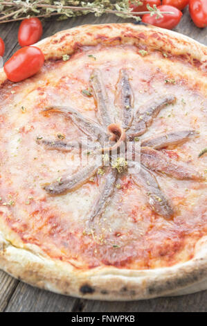 Acciughe e pomodoro pizza sul tavolo di legno Foto Stock