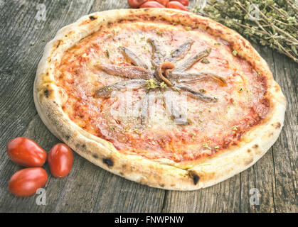 Acciughe e pomodoro pizza sul tavolo di legno Foto Stock