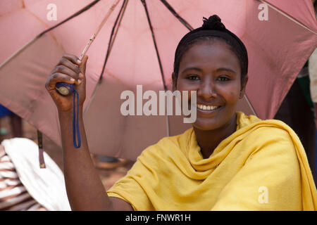 Una donna sfumature se stessa dal sole con un ombrello, Etiopia Africa Foto Stock