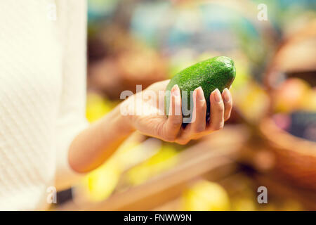 Close up donna mano azienda avocado nel mercato Foto Stock