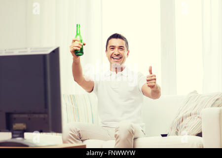 Uomo sorridente di guardare la tv e bere birra in casa Foto Stock