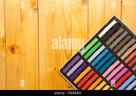 Pastelli colorati in una casella su un sfondo di legno Foto Stock