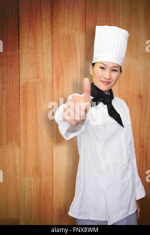 Immagine composita di sorridere cuoca gesticolando pollice fino in cucina Foto Stock