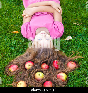 Ragazza distesa sul prato con le mele nei suoi capelli, concept Foto Stock