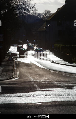 Automobili pick il loro cammino lungo una strada allagata riflessa in condizioni di luce solare intensa. Foto Stock