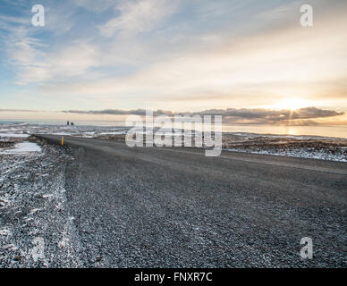 Vuoto su strada asfaltata che conduce nella distanza verso il tramonto in inverno Foto Stock