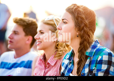 Gli adolescenti presso i festival estivi di musica, seduto a terra Foto Stock