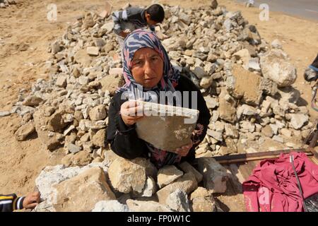 Marzo 17, 2016 - Khan Yunis, Striscia di Gaza, Territori palestinesi - donna palestinese Abu JIHAN MUHSEN raccoglie mattoni per la vendita con suo figlio Mohammad dalle rovine di una casa distrutta durante la guerra 2014 in Khan Younis nel sud della striscia di Gaza. Abu Muhsen raccoglie mattoni dai siti di edifici demoliti e li vende alle fabbriche di riciclaggio. Lei guadagna circa venti sicli ($5) un giorno e suoi 10-anno-vecchio figlio Mohammad aiuta la sua quando egli non è a scuola (credito Immagine: © Ashraf Amra/APA immagini via ZUMA filo) Foto Stock