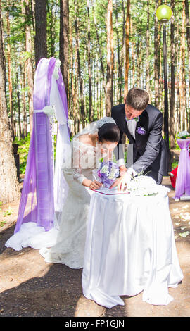 Sposa e lo sposo di lasciare le loro firme sulla cerimonia di nozze Foto Stock