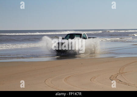 La guida di automezzi pesanti attraverso l'acqua su una spiaggia Foto Stock