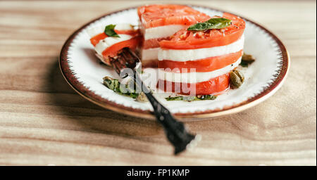 Insalata caprese con strati di mozzarella di bufala e cimelio di pomodori con basilico fresco, capperi e olio di oliva. Foto Stock