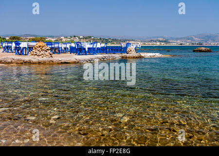 Tavoli con sedie in una tradizionale taverna Greca Kolympia nella cittadina sulla costa dell'isola di Rodi, Grecia. Foto Stock