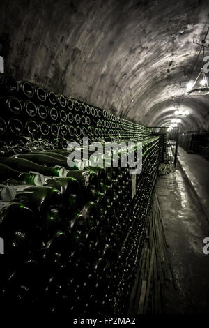 Il rack con bottiglie di vino spumante in un unico tunnel di montagna Foto Stock