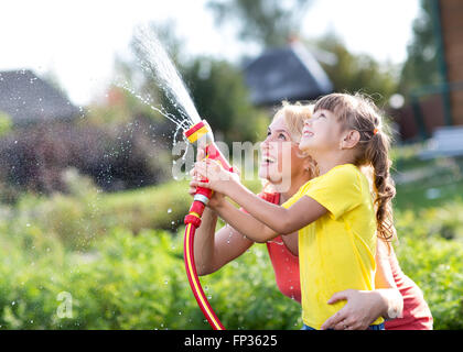 Piccolo giardiniere ragazza con irrigazione madre sul prato vicino casa Foto Stock