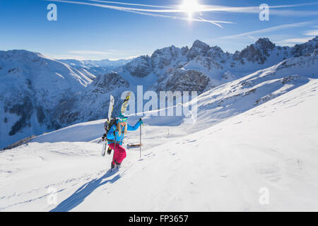 Giovane donna con gli sci ancorato sul suo zaino salendo snowcovered montagna, Axamer Lizum, Innsbruck, in Tirolo, Austria Foto Stock
