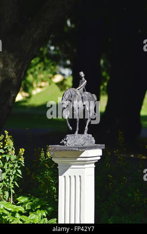 Una scultura in miniatura di un ragazzo sul cavallo nel giardino di un estate giornata di sole. Foto Stock