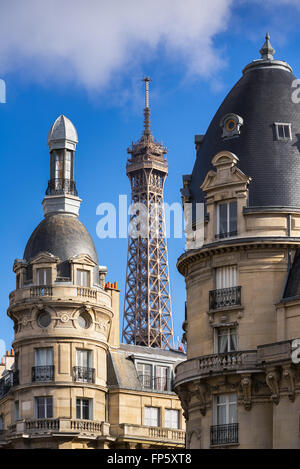 Parte superiore della torre Eiffel incorniciata tra torri di edifici in stile Haussmann nel XVI Arrondissement. Parigi, Francia Foto Stock