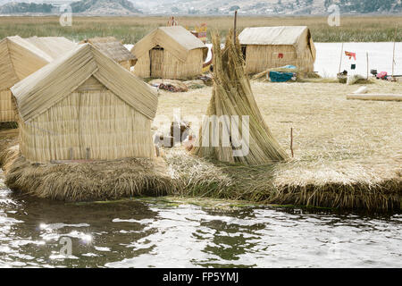 Le case su Uros isole galleggianti fatte di tortora giunchi, il lago Titicaca, Perù. Il cibo viene cotto con fuochi collocati su pali di pietre. Le isole galleggianti sono protetti all'interno della baia di Puno e sono la casa di 2000 o in modo Uros, che affermano di aver "sangue nero' sono di conseguenza immune a freddo. Loro si chiamano essere kosuña, o persone del lago, e si considerano i proprietari del lago e le sue acque. Foto Stock