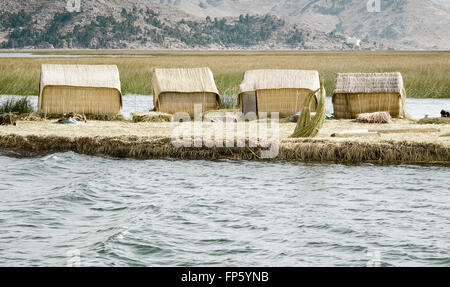 Le case su Uros isole galleggianti fatte di tortora giunchi, il lago Titicaca, Perù. Il cibo viene cotto con fuochi collocati su pali di pietre. Le isole galleggianti sono protetti all'interno della baia di Puno e sono la casa di 2000 o in modo Uros, che affermano di aver "sangue nero' sono di conseguenza immune a freddo. Loro si chiamano essere kosuña, o persone del lago, e si considerano i proprietari del lago e le sue acque. Foto Stock