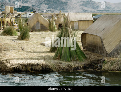 Le case su Uros isole galleggianti fatte di tortora giunchi, il lago Titicaca, Perù. Il cibo viene cotto con fuochi collocati su pali di pietre. Le isole galleggianti sono protetti all'interno della baia di Puno e sono la casa di 2000 o in modo Uros, che affermano di aver "sangue nero' sono di conseguenza immune a freddo. Loro si chiamano essere kosuña, o persone del lago, e si considerano i proprietari del lago e le sue acque. Foto Stock